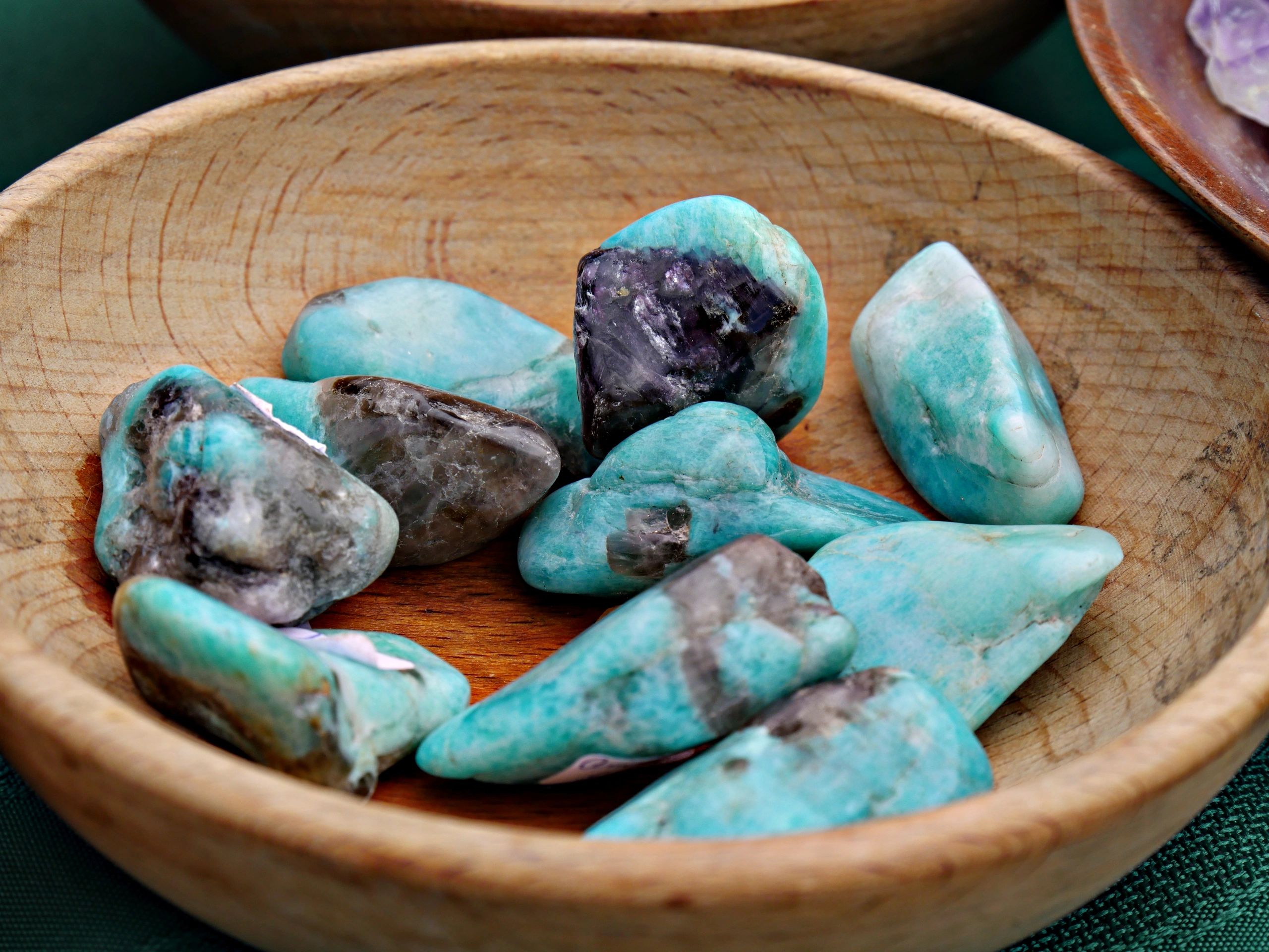 Colorful rough gemstones in a wooden bowl
